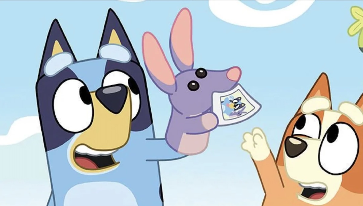 Two animated dog pups play with a rabbit hand puppet in "Bluey"