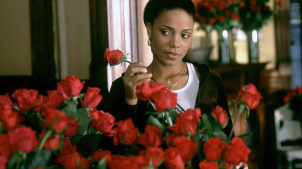 A woman looks amorously over roses in "Brown Sugar"