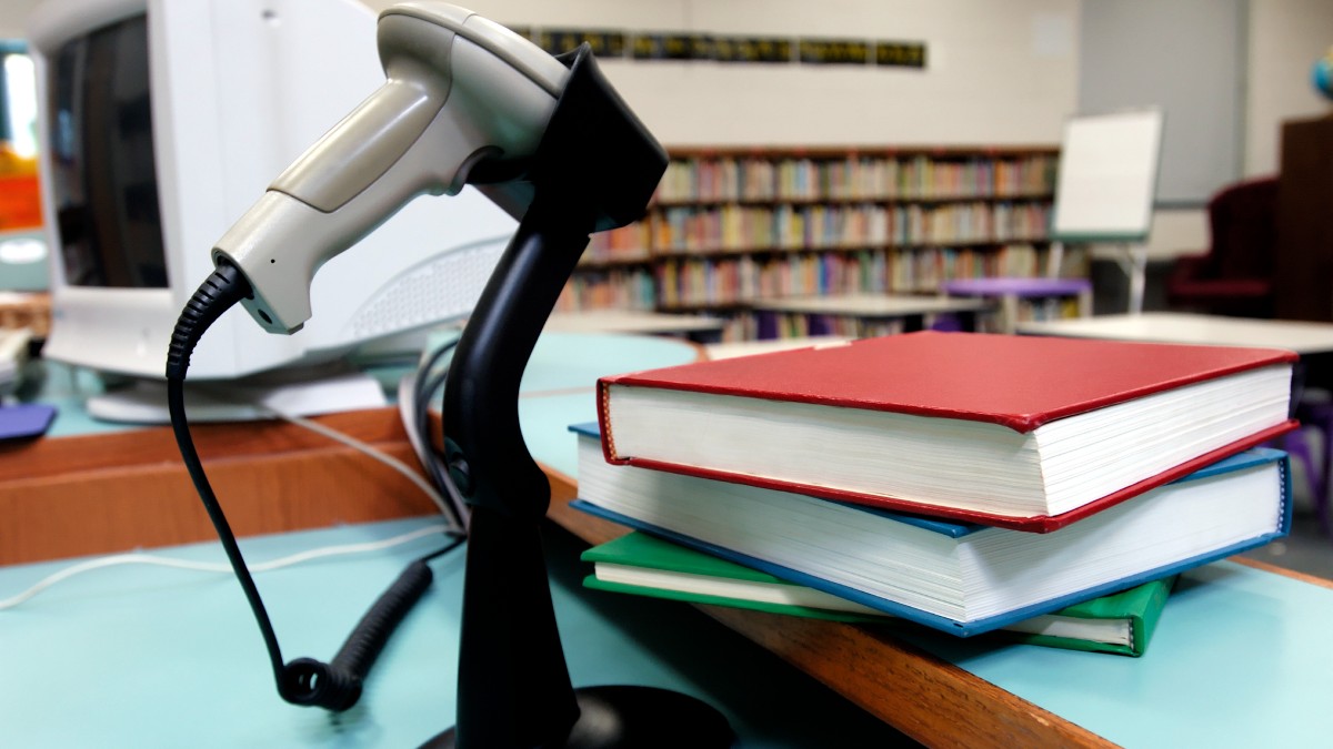 Library books sitting next to a bar code scanner