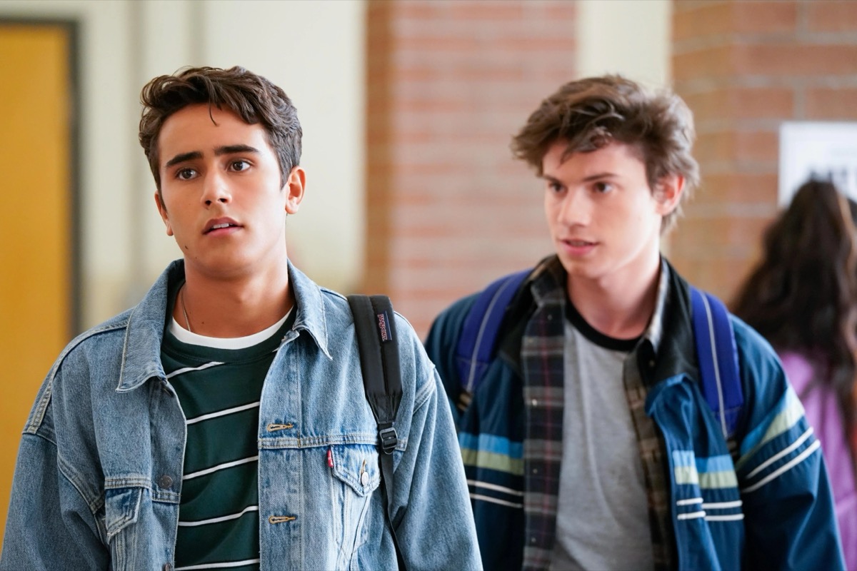 A teenage gay couple stand beside each other in the high school halls in "Love, Victor"