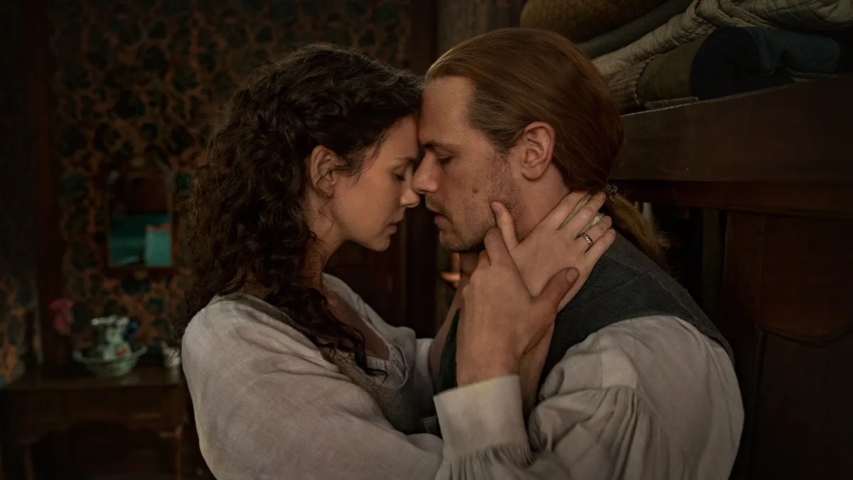 An 18th century man and woman lean in to kiss in "Outlander"