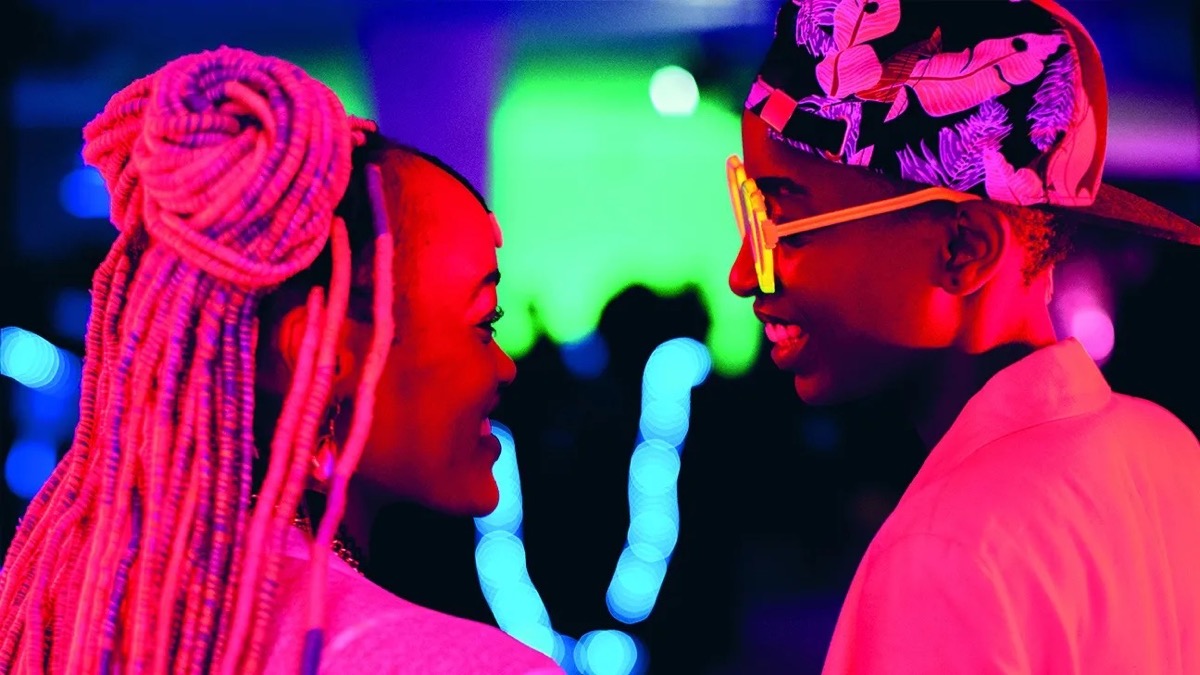 Two neon lit women smile at each other in "Rafiki" 