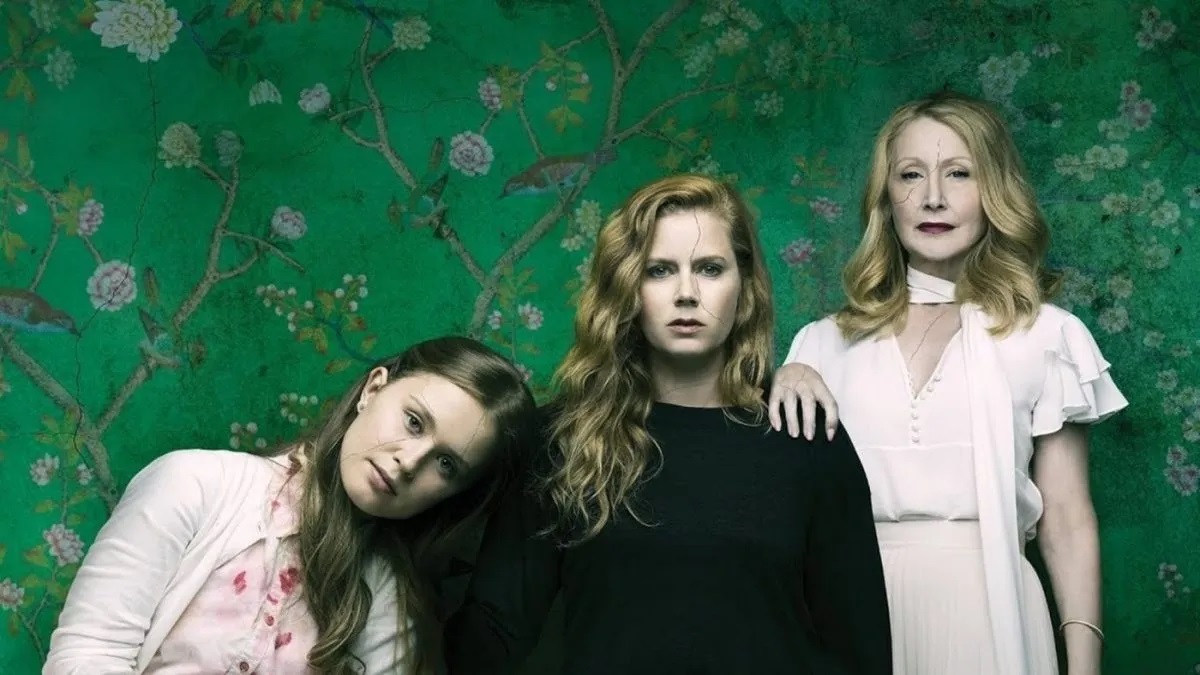 Three woman stand against a green background in promo art for 'Sharp Objects' 