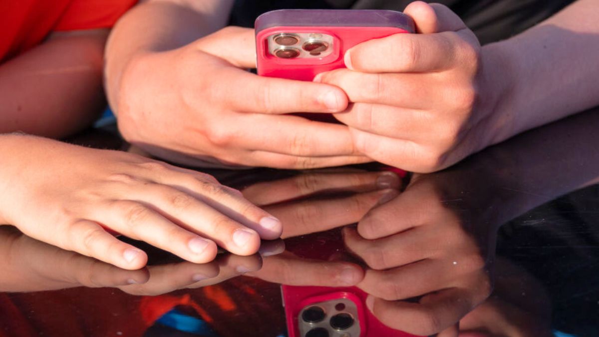 PENZANCE, UNITED KINGDOM - AUGUST 15: A 12 and a 13-year-old boy look at a iPhone screen on August 15, 2024 in Penzance, England. The amount of time children spend on screens each day rocketed during the Covid pandemic by more than 50 per cent, the equivalent of an extra hour and twenty minutes. Researchers say that unmoderated screen time can have long-lasting effects on a child's mental and physical health. Recently TikTok announced that every account belonging to a user below age 18 have a 60-minute daily screen time limit automatically set. (Photo by Matt Cardy/Getty Images)