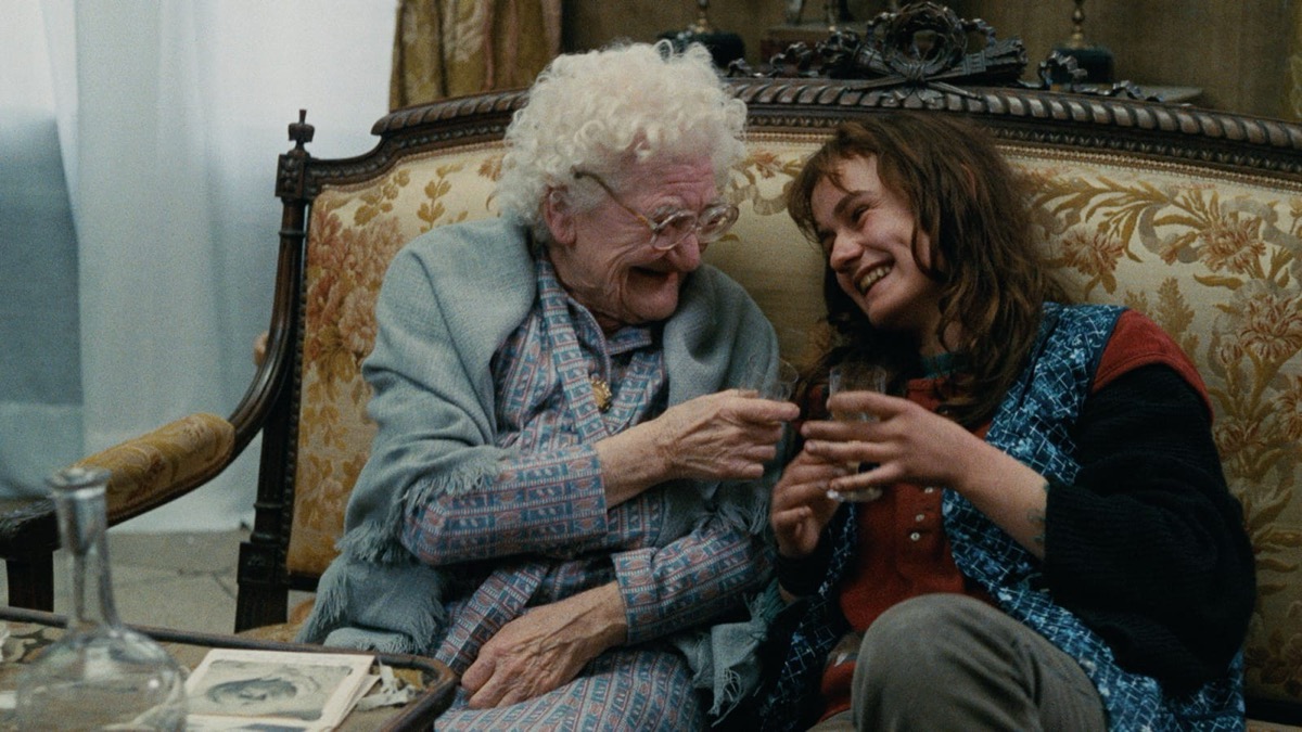 A young woman and an old woman laugh together on a couch