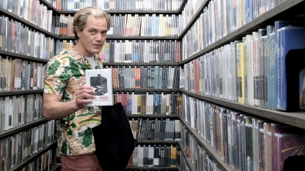 Michael Shannon standing in the criterion closet surrounded by movies