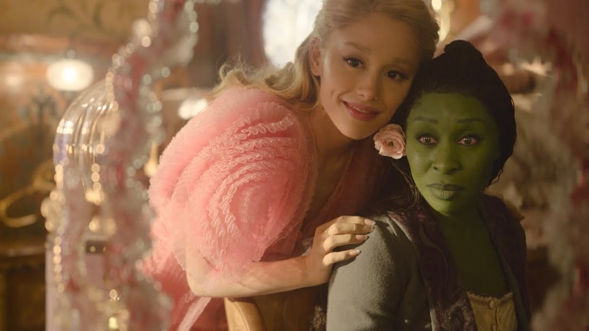 L-R: Ariana Grande as Glinda and Cynthia Erivo as Elphaba from Wicked. The two are looking at each other in a mirror.