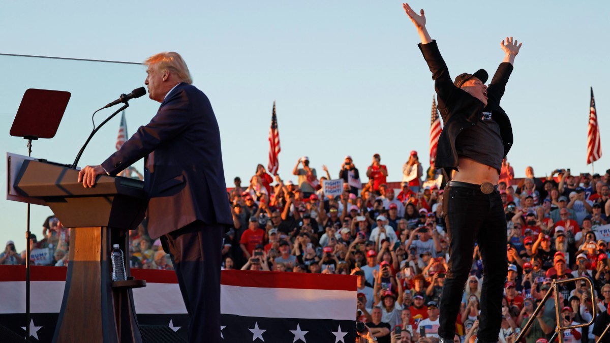 Elon Musk jumping around on stage while Donald Trump speaks at a Trump rally