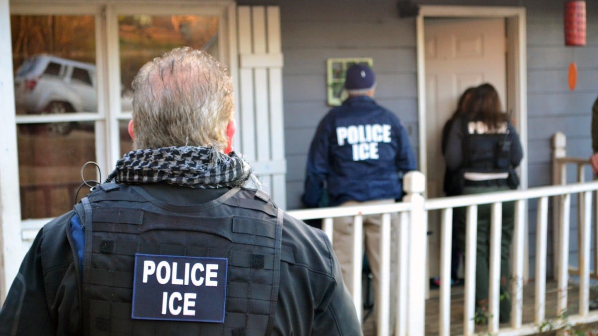 ICE officers stand outside a home