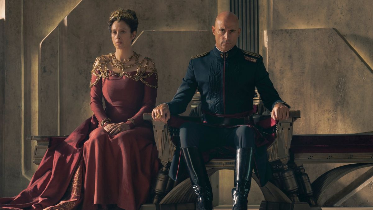 Jodhi May as Empress Natalya and Mark Strong as Emperor Javico Corrino sit on the Golden Lion Throne in Dune: Prophecy