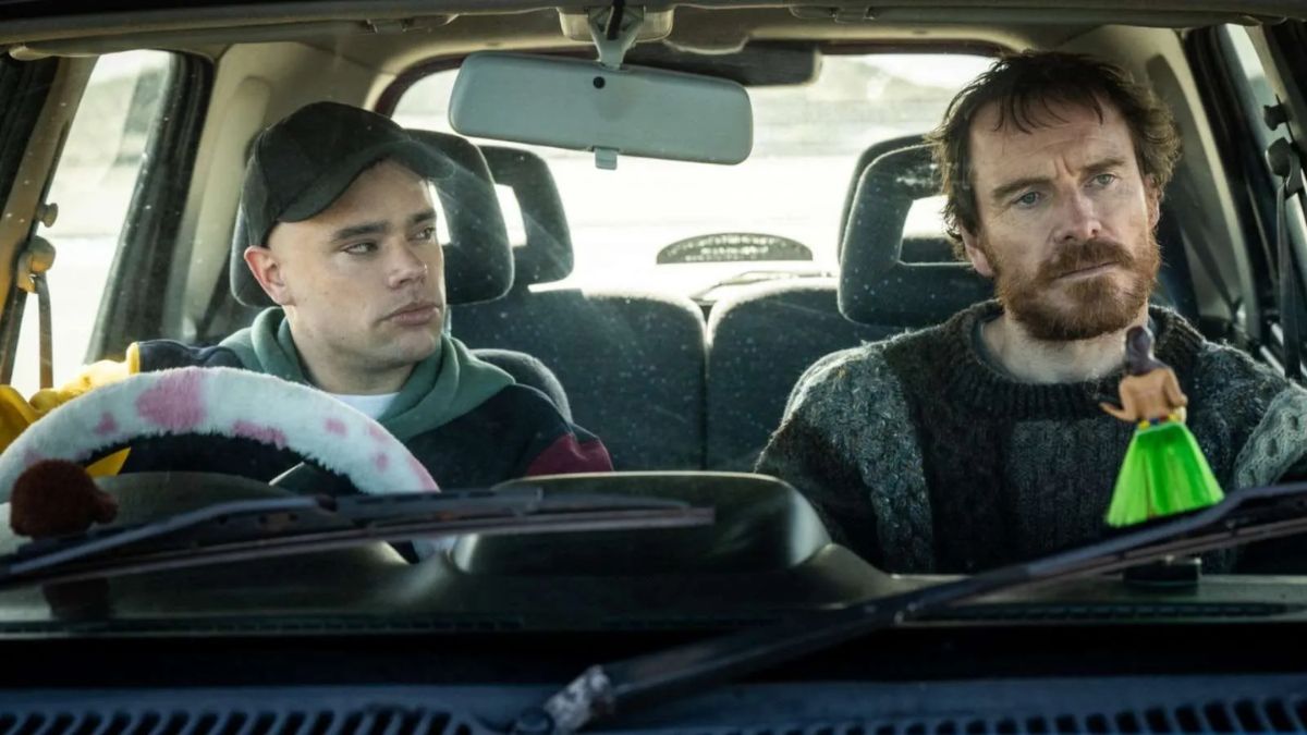 Two men, one younger and one middle-aged, sitting in a car.