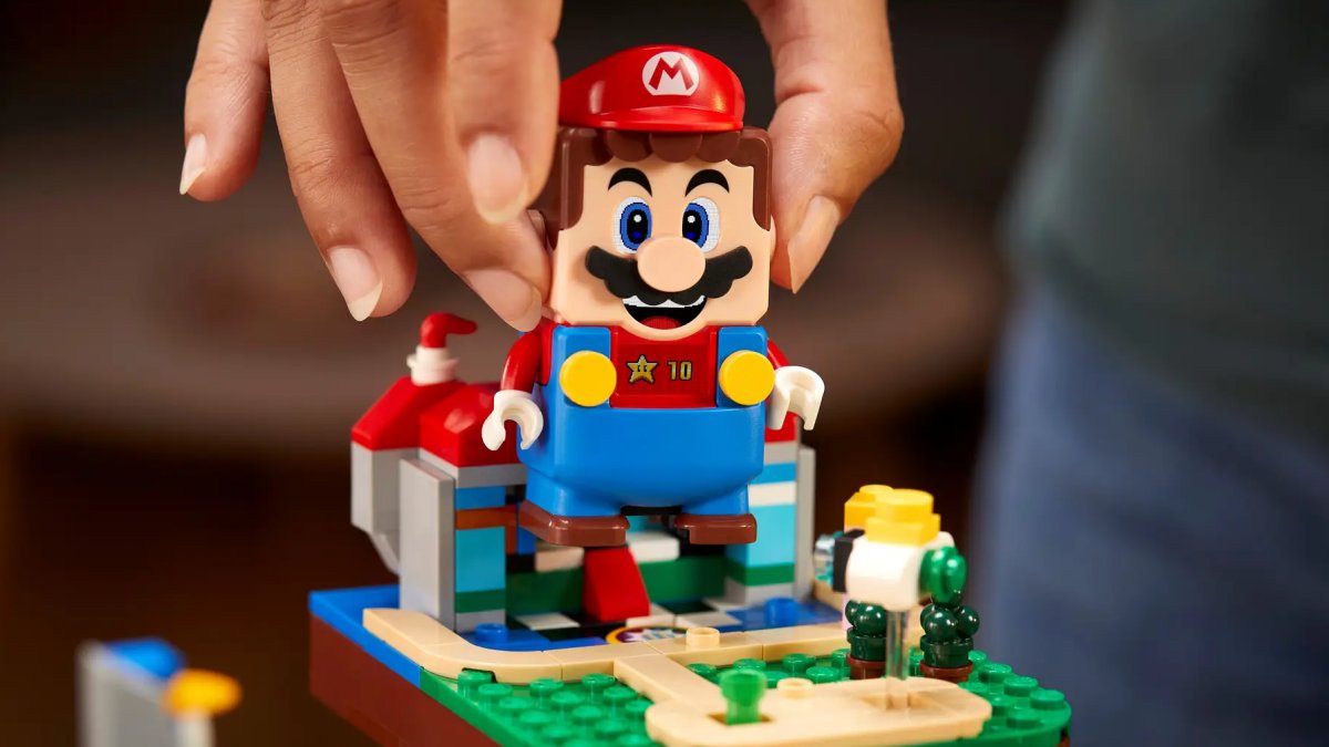 A hand controlling a LEGO Super Mario