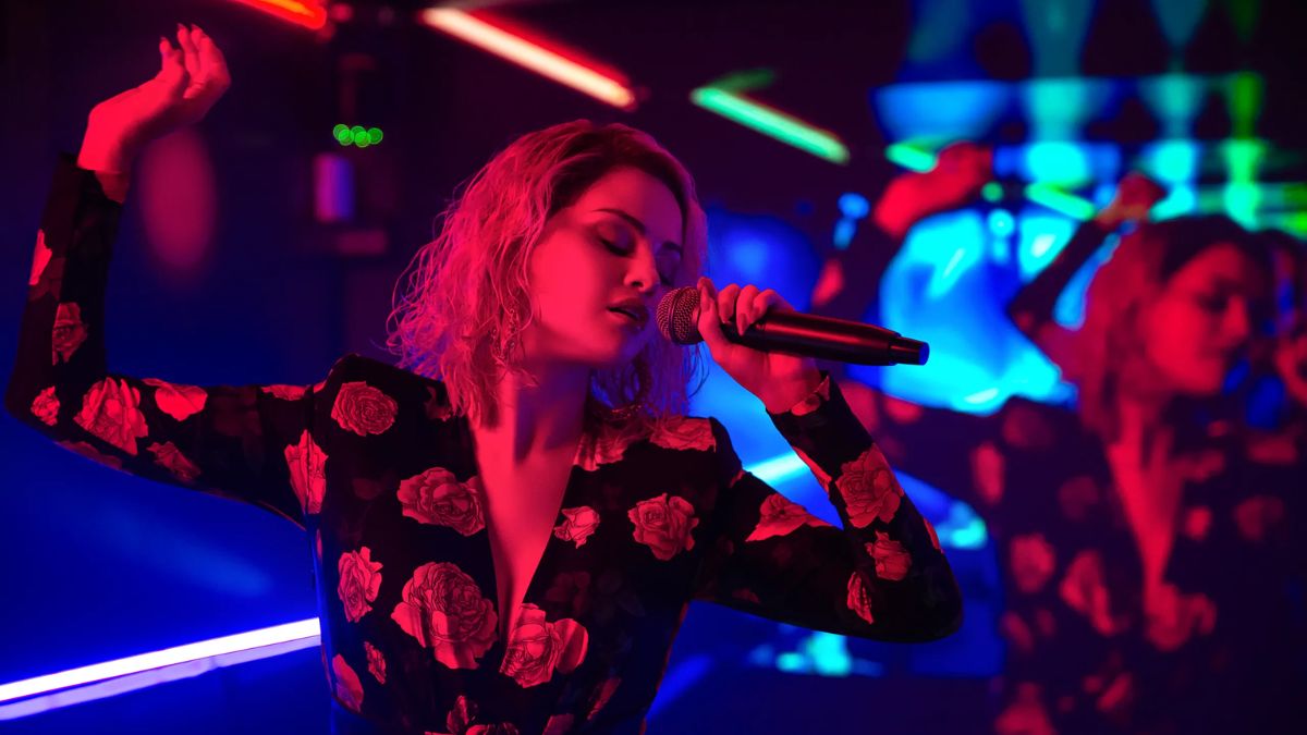 Selena Gomez as Jessi sings into a mic at a nightclub in Emilia Pérez