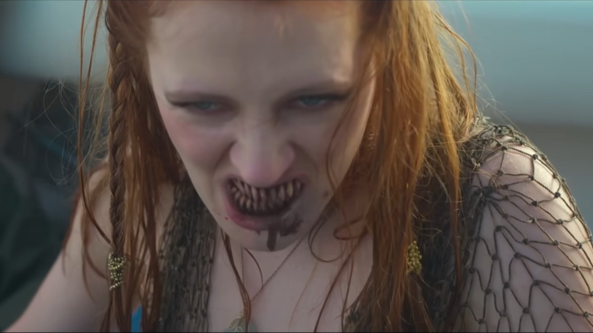 A red-headed mermaid bares her bloody sharp teeth.