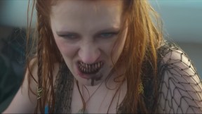 A red-headed mermaid bares her bloody sharp teeth.