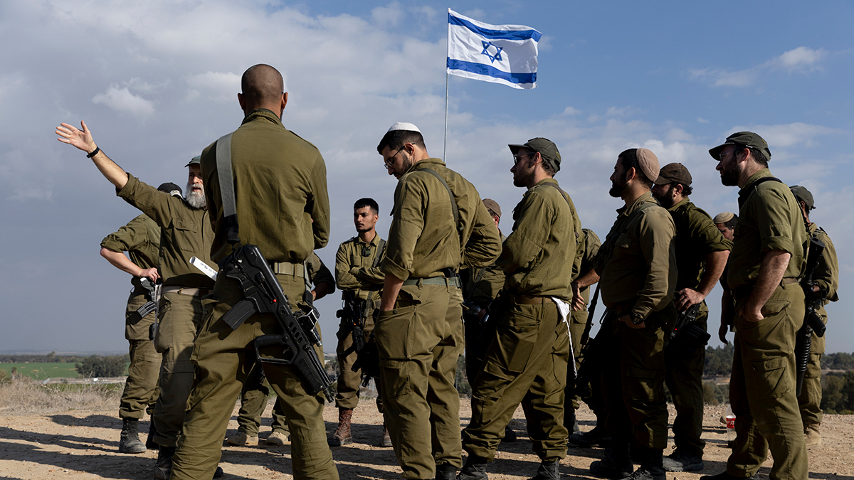 SOUTHERN ISRAEL, ISRAEL - DECEMBER 5: Soldiers stand near an Israeli flag as they receive a briefing near the border with the Gaza Strip on December 5, 2024 in Southern Israel, Israel . Egyptian and Qatari mediators have given Hamas an updated version of a ceasefire deal proposal that involves the release of the remaining 100 hostages with the Israeli defence minister, Israel Katz, was optomistic yesterday at the likelihood of securing a deal. (Photo by Amir Levy/Getty Images)