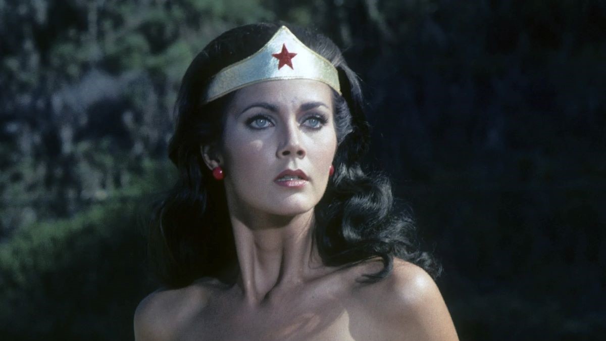 Image of Lynda Carter as Wonder Woman from the 1970s 'Wonder Woman' TV show. She is a white Latina with long, dark hair wearing Wonder Woman's gold tiara w/red star in the center and red earrings. She's looking off into the distance.