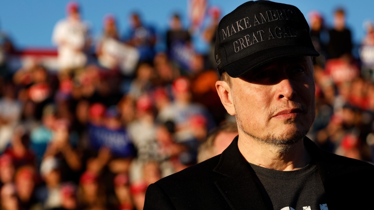 Elon Musk wears a black MAGA hat at a Donald Trump rally