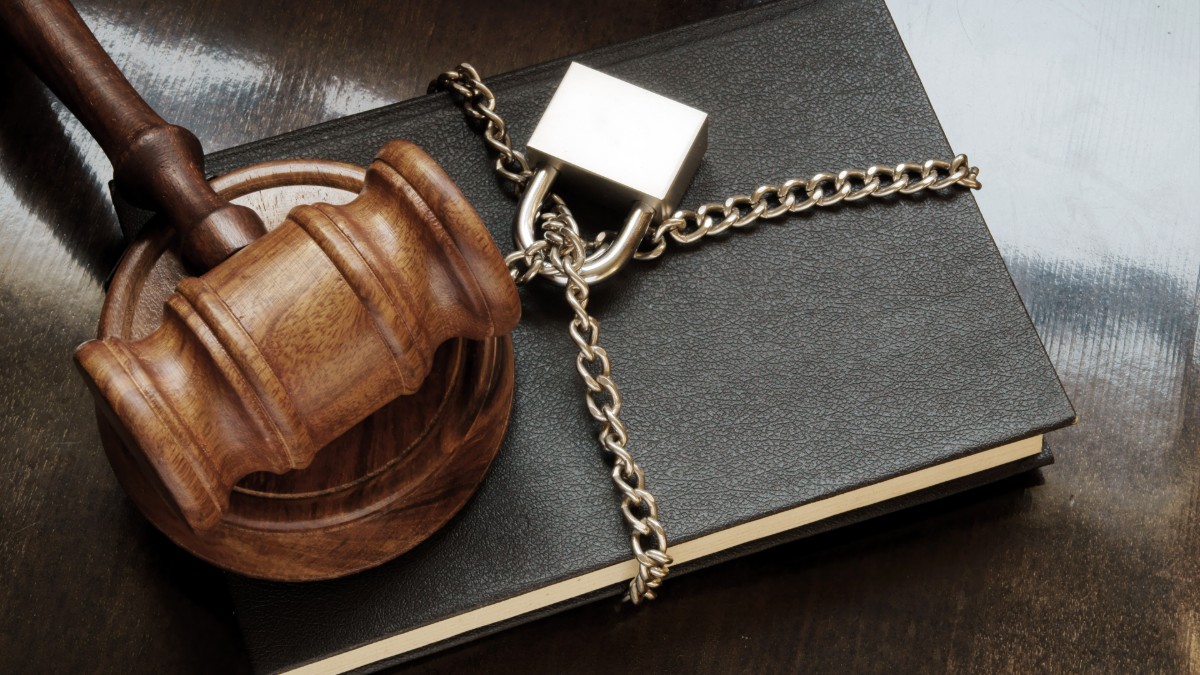 A judge gavel resting on a chained and padlocked book