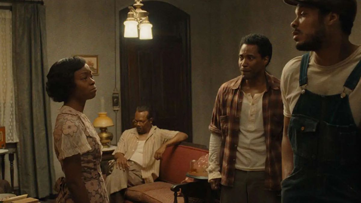 A woman stands facing two men in a home