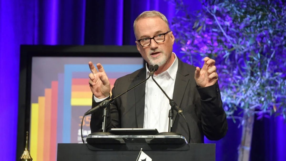 A bespectacled man speaks on stage during an awards ceremony