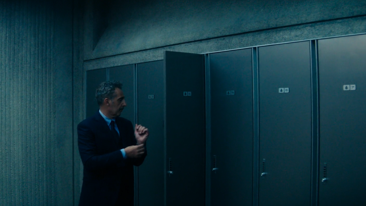 John Tuturro adjusts his cuffs in front of his locker number 4 on Severance