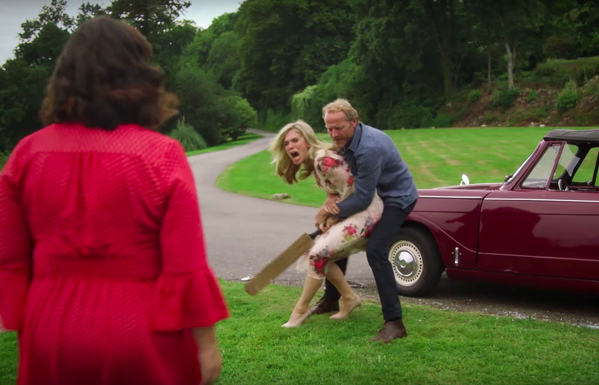 A woman holding a cricket bat is restrained by a man while another woman looks on in "Delicious"