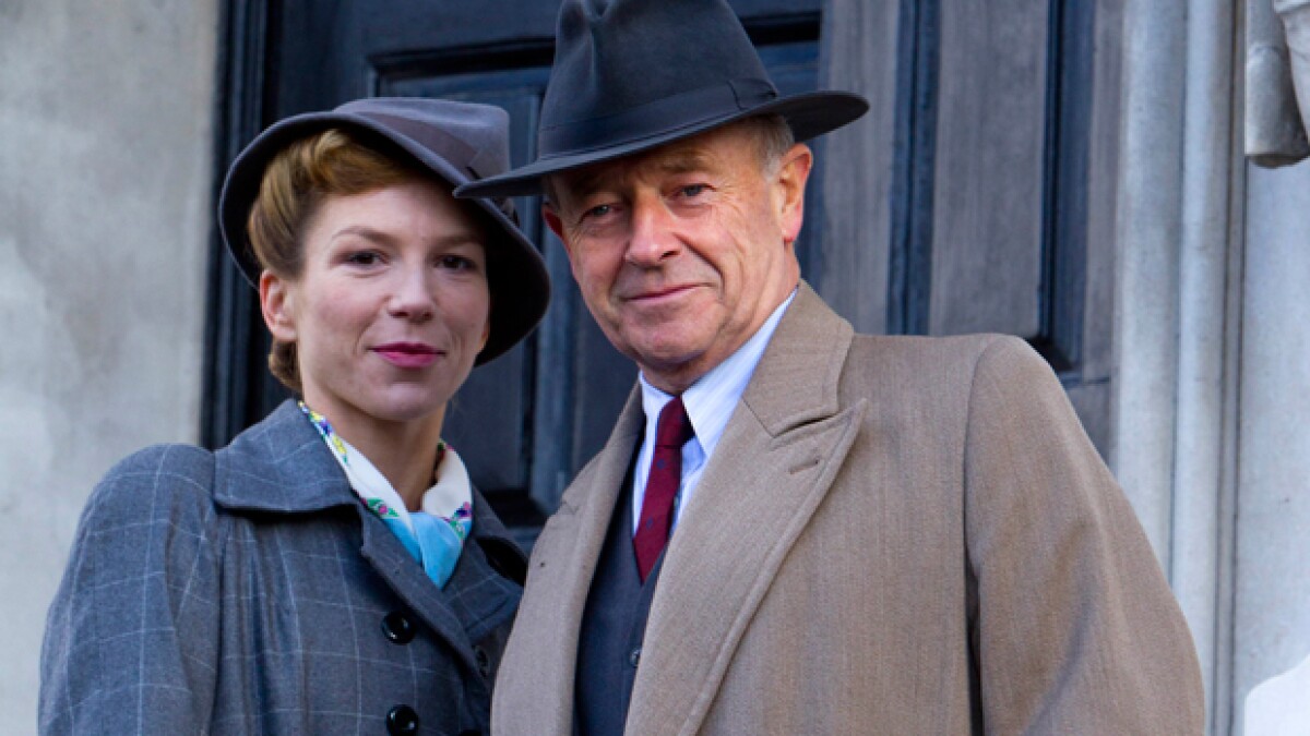 A middle-aged 1940's British couple smiles into the camera in "Foyle's War"