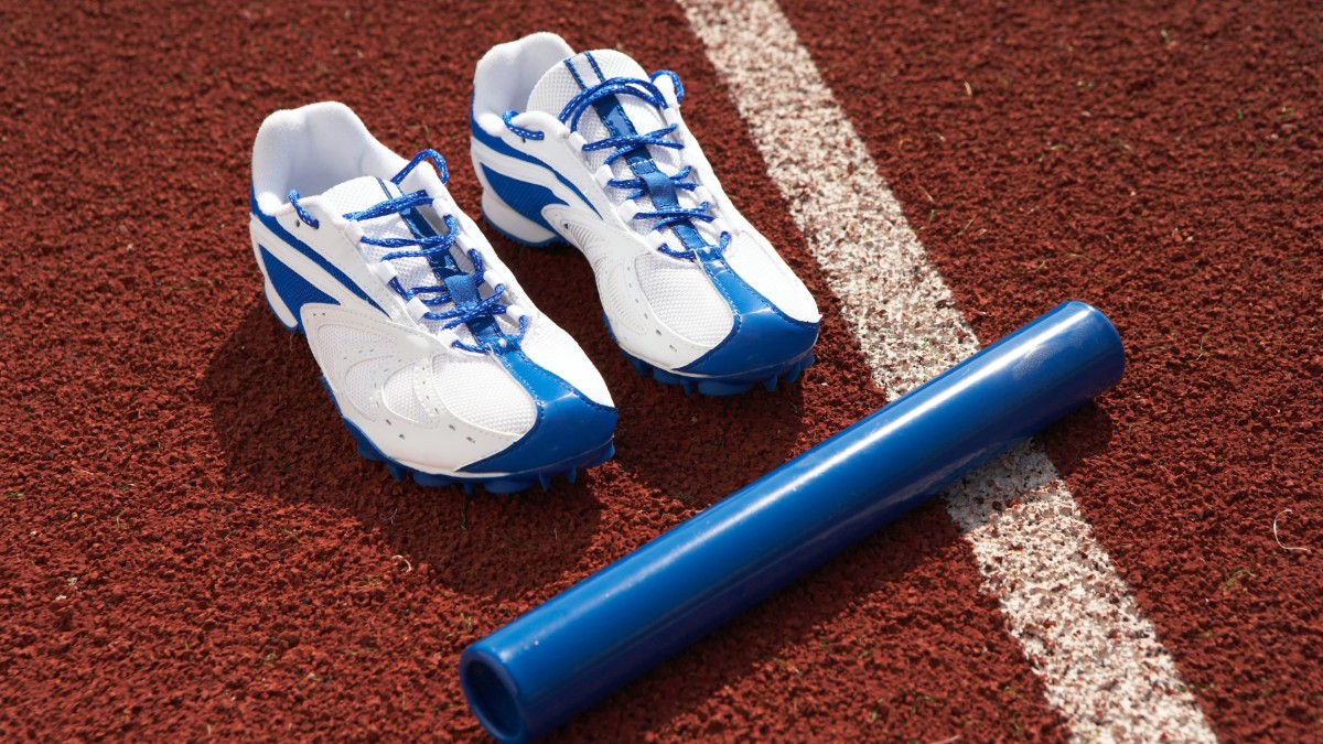 Track shoes sitting next to a relay baton on the track